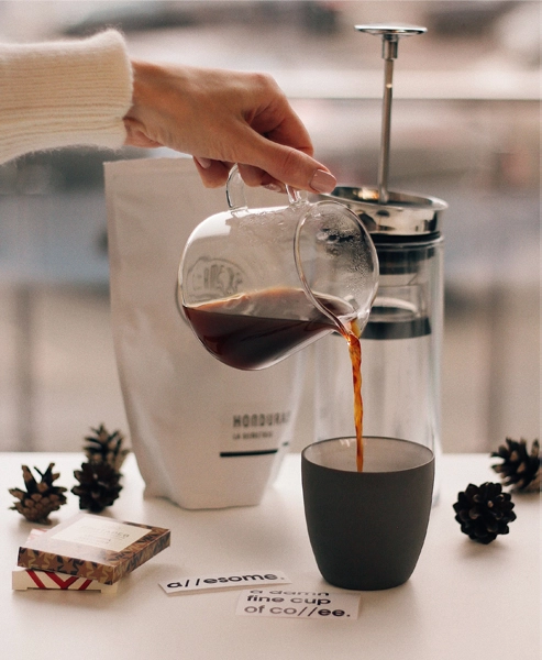 A lady making a coffee by pouring water with a kettle on her hand