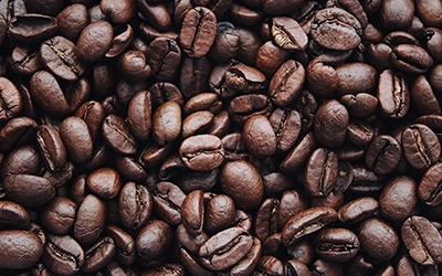 Picture of a lots of coffee beans spread all over on the canvas.